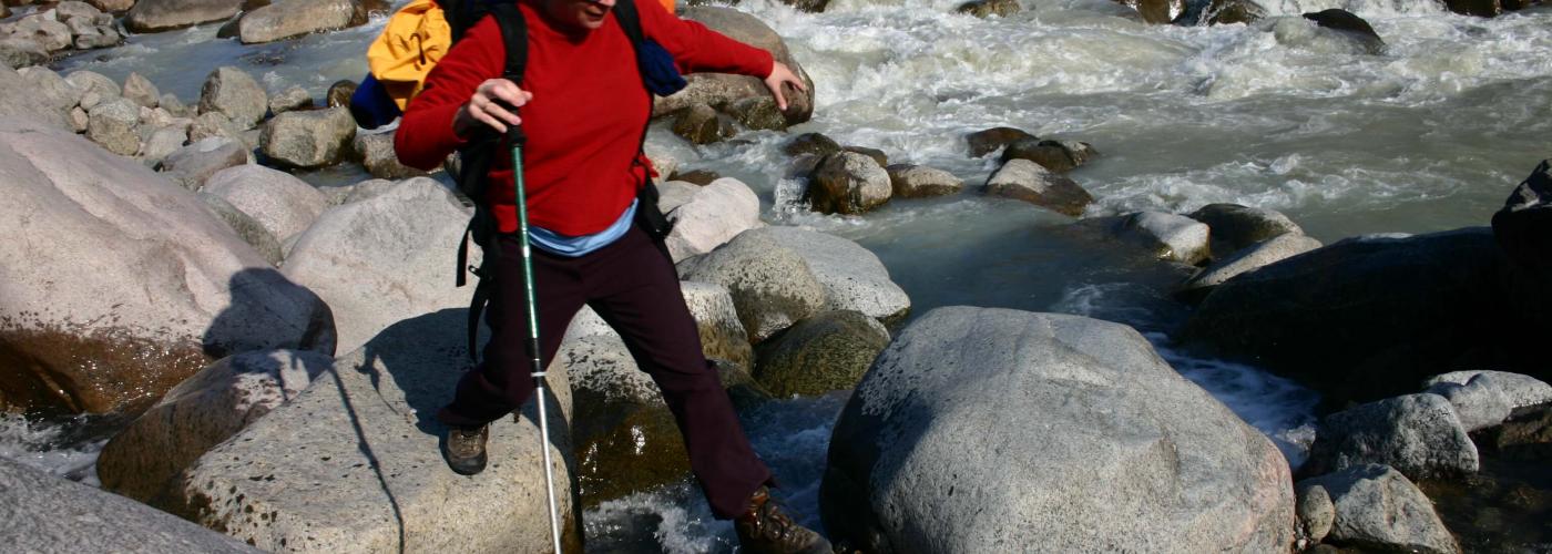 Adventurer walking across rocky stream